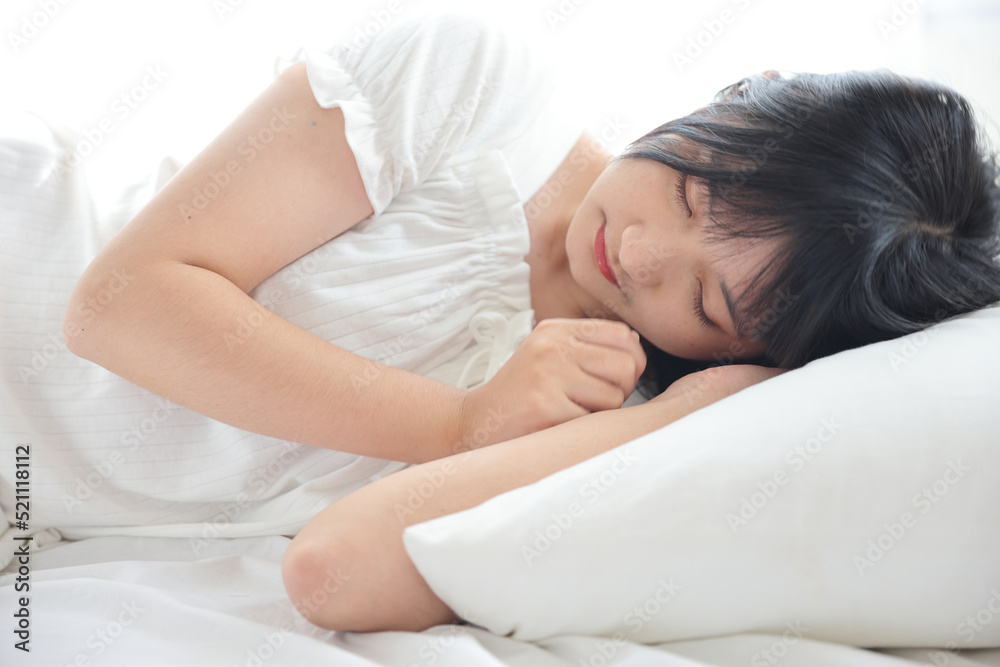Beautiful young Asian woman sleeping on bed relaxing in the morning light with white room Beautiful young Asian woman sleeping on bed relaxing in the morning light with white room