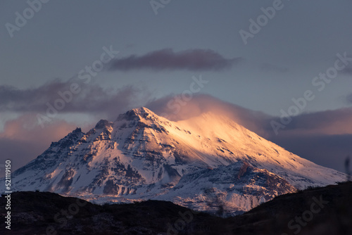 gran montaña nevada en atardecer con nubes y vapor, atardecer rosado, majestuosa montaña  photo