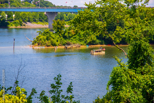 people on colorful paddle boards on the rippling waters of the Tennessee River surrounded by lush green trees on Maclellan Island in Chattanooga Tennessee USA photo