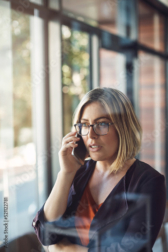 Young business woman on the phone making a call in a modern office. Female standing alone at work calling on smartphone, talking or speaking to company clients in her workplace