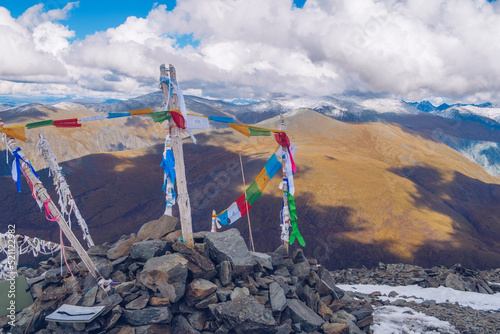 Sacred shamanic stone pile decorated with colored ribbons on the top of the mountain pass with mountain valley picturesque view. Marvelous mountain range. Altai mountains.