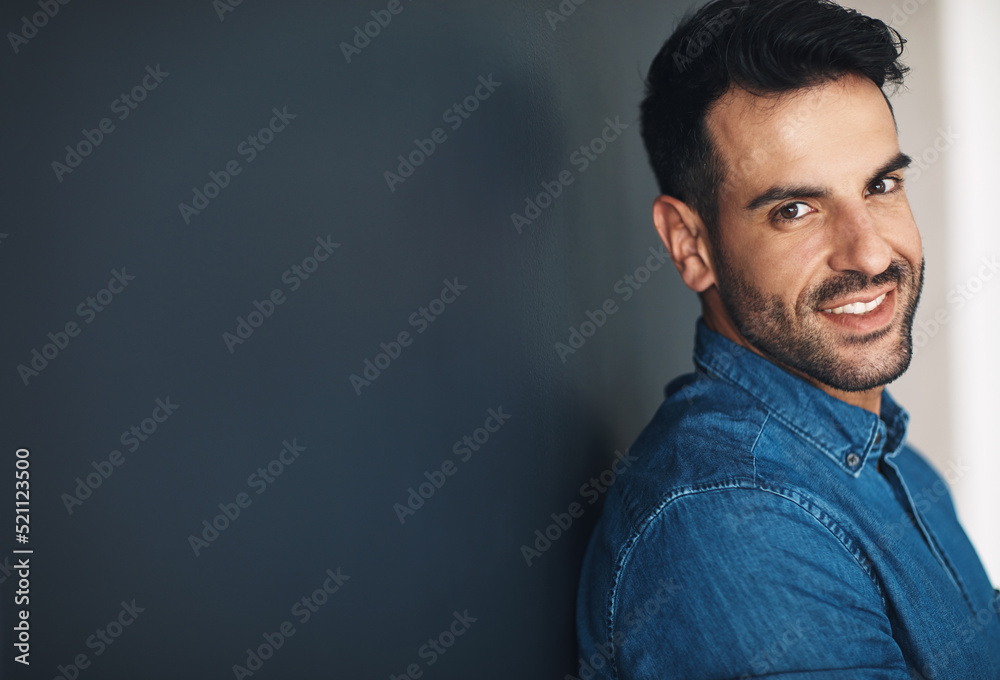 Fototapeta premium Happy, confident and smiling business man or entrepreneur in an office with copy space. Ambitious and determined male employee leaning against a wall at work. Feeling positive and working for success