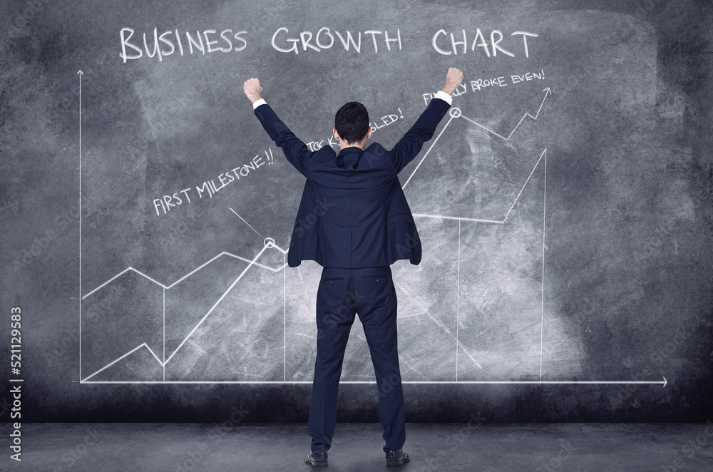 Finance business man cheering in success looking at a cgi graph, chart and data against a black background. Boss analysing, examining and celebrating startup company growth from behind Finance business man cheering in success looking at a cgi graph, chart and data against a black background. Boss analysing, examining and celebrating startup company growth from behind
