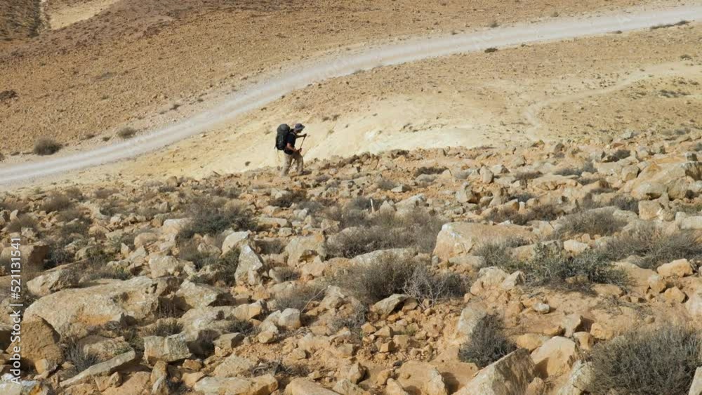 High angle shot of a hiker walking on the rocky slope on Mount Ramon ...