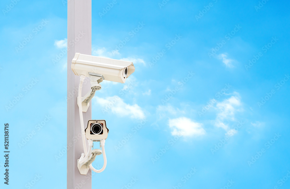 Outdoor white CCTV on pole with blue sky background and copy space