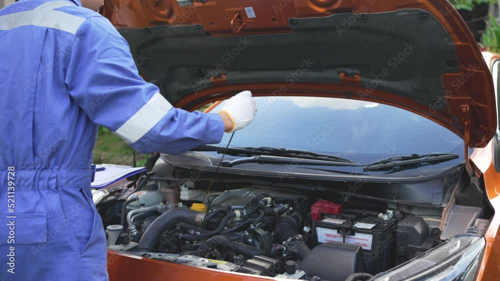 Mechanic checking engine oil level Engine that has completed the service period. The concept of checking the condition of the car before leaving. Mechanic checking engine oil level Engine that has completed the service period. The concept of checking the condition of the car before leaving.