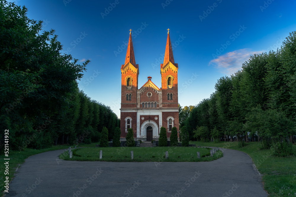 Medieval red brick church with two towers in sunset light.