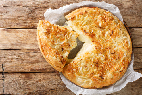 Fugazzeta Argentinian deep dish pizza stuffed with mozzarella cheese and topped with parmesan cheese and toasted onions closeup in the plate on the wooden table. Horizontal top view from above photo