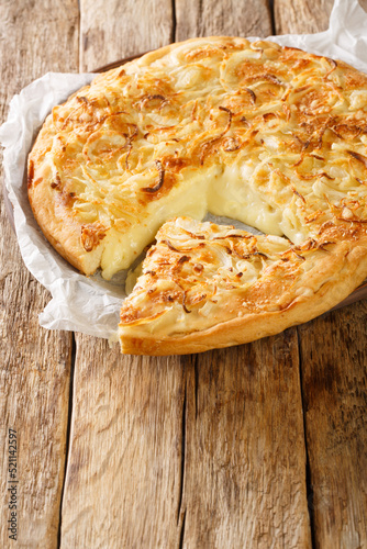 Argentinian Pizza Fugazzeta stuffed with cheese, and topped with the same sweet onions closeup in the plate on the wooden table. Vertical photo