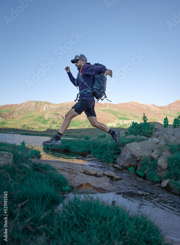 Deportista saltando río en la montaña, trail running