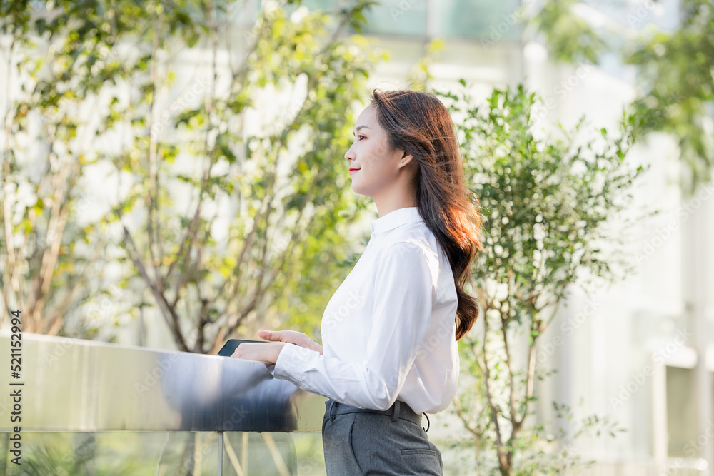 Business woman looking into the distance in front of outdoor railing Business woman looking into the distance in front of outdoor railing