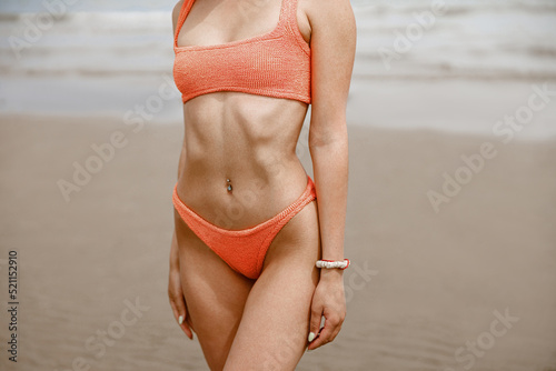 Close up sexy woman at beach in swimsuit with ideal fitness body on background of ocean