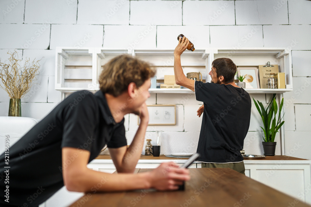 Obraz premium Two guys have fun in the kitchen using a digital tablet online