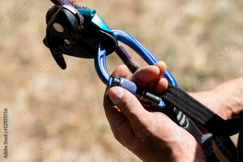 Close up shot of a man's hands operating a rock climbing assisted belaying device