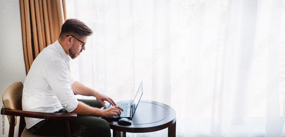 Male businessman in a white shirt working at a laptop in the office, during a conversation, online meeting, remote work.