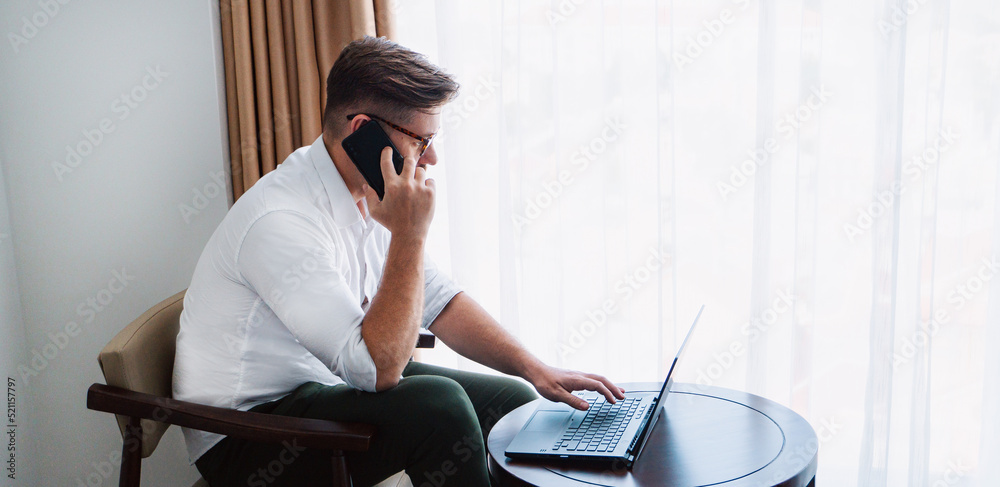 Male businessman in a white shirt working at a laptop in the office, during a conversation, online meeting, remote work.
