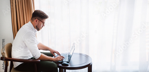 Obraz na płótnie Male businessman in a white shirt working at a laptop in the office, during a conversation, online meeting, remote work. w salonie