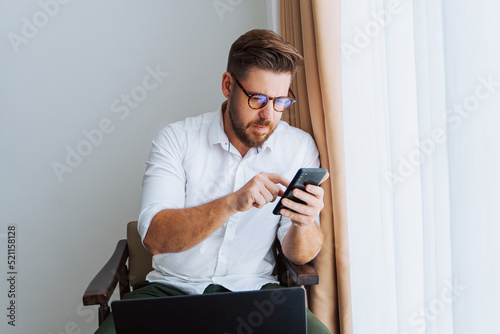 Obraz na płótnie Male businessman in a white shirt working at a laptop in the office, during a conversation, online meeting, remote work. w salonie