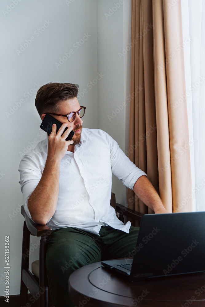 Male businessman in a white shirt working at a laptop in the office, during a conversation, online meeting, remote work.