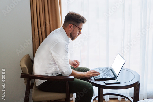 Obraz na płótnie Male businessman in a white shirt working at a laptop in the office, during a conversation, online meeting, remote work. w salonie