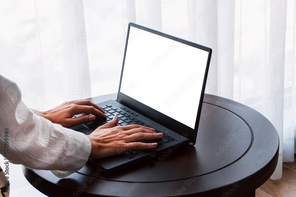 Person working at a laptop, close-up of hands and computer screen, remote work on a light background.
