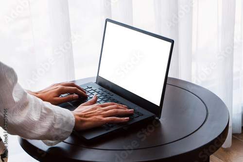 Person working at a laptop, close-up of hands and computer screen, remote work on a light background.