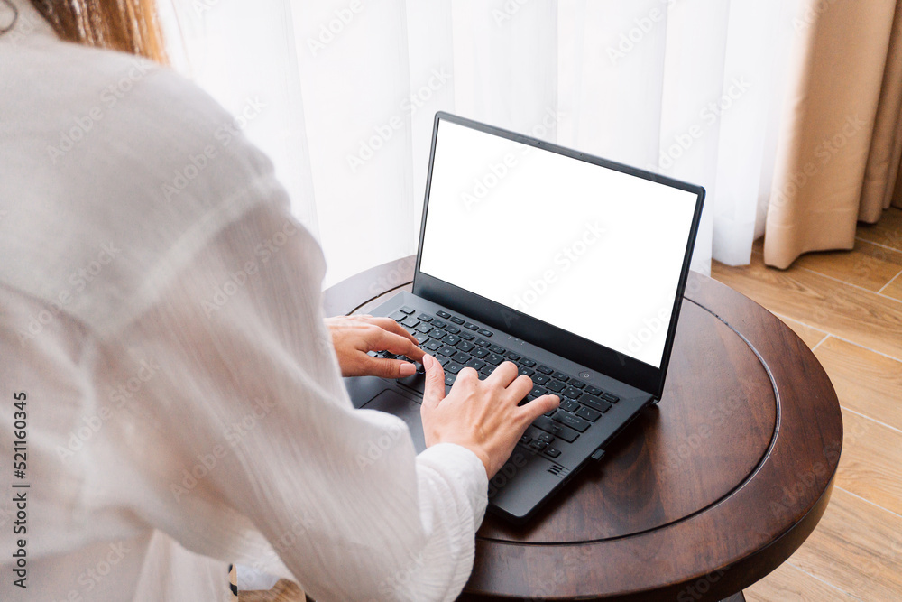 Person working at a laptop, close-up of hands and computer screen, remote work on a light background.