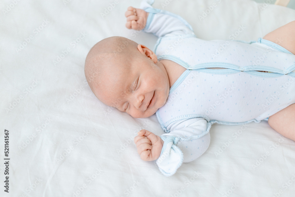 smiling or laughing in a dream, a newborn baby boy sleeps for seven days in a cot at home on a cotton bed, close-up smiling or laughing in a dream, a newborn baby boy sleeps for seven days in a cot at home on a cotton bed, close-up
