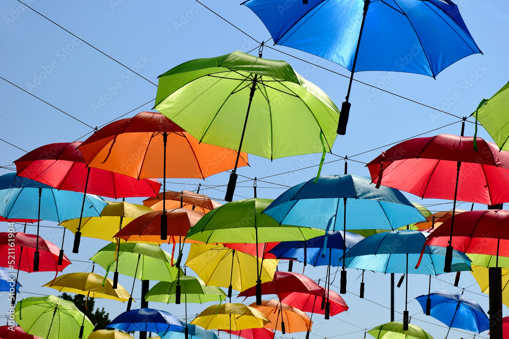 colorful parasol sun protection. bright umbrellas suspended overhead on metal wires. climate change and global warming concept. summer travel tourism and vacation theme. design and urban environment. 