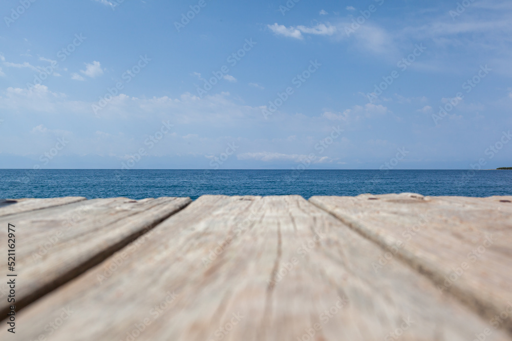 Wooden planks on the pier above the blue sea. Wooden planks on top of the water.