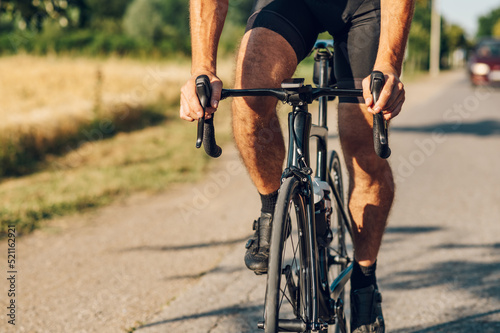 Cropped shot of an athletic man in sport clothes riding a bike in the nature