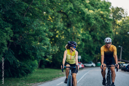 Fototapeta Naklejka Na Ścianę i Meble -  Couple riding road bicycles outside and wearing helmets and sunglasses
