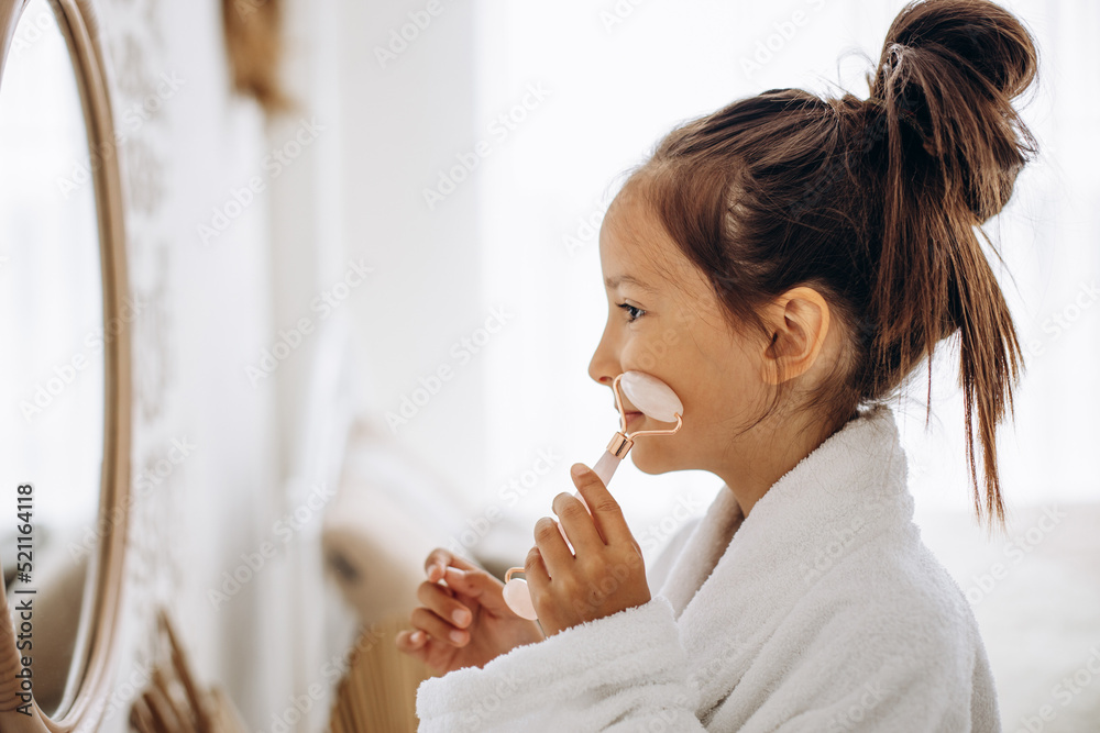 Girl doing self massage with rose quartz face roller Girl doing self massage with rose quartz face roller