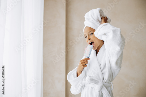 Cute preteen girl singing using hair brush as a microphone