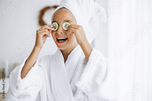 Cute girl wearing bathrobe and towel on head with cucumbers photo
