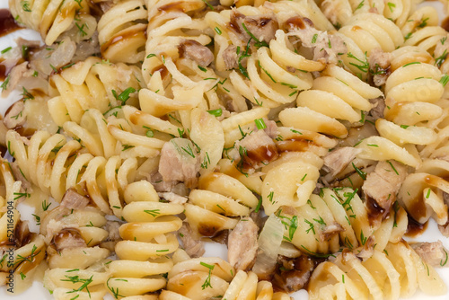 Prepared spiral pasta with chopped meat and dill close-up photo