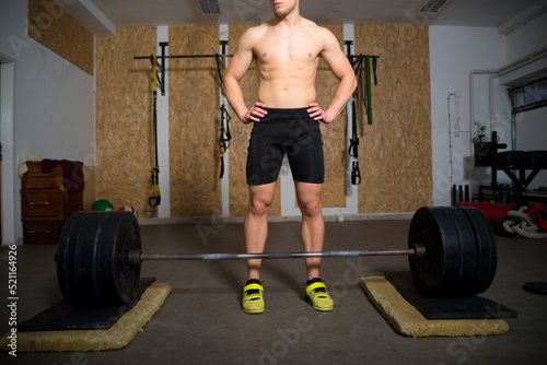 Young strong man lifting heavy weights in sports gym
