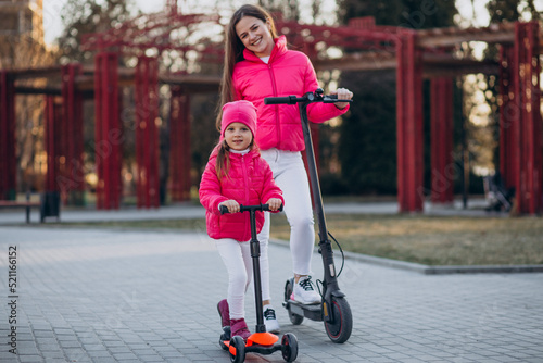 Mother with daughter riding electric scooter