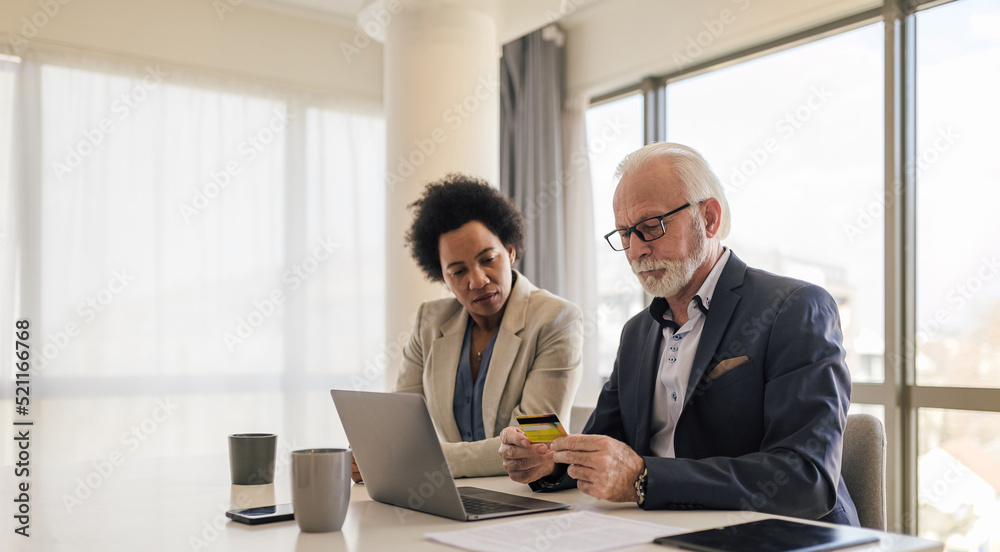 Professionals doing online transaction through credit card on laptop at the office. Professionals doing online transaction through credit card on laptop at the office.