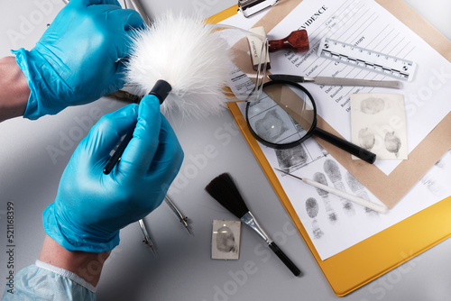 Forensic fingerprinting, forensic expert handles a glass goblet with a fingerprint brush