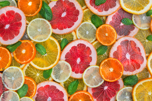 Ripe juicy citrus fruits are cut into slices and mint. Food background.