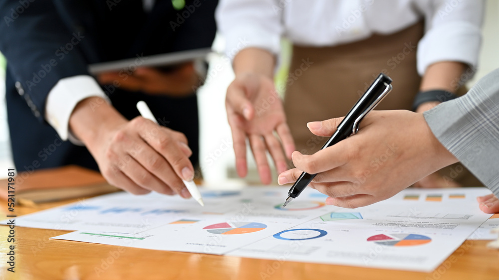 A professional financial analyst team is working and brainstorming. pen pointing on the report A professional financial analyst team is working and brainstorming. pen pointing on the report