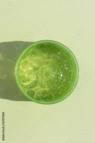 A container with a transparent hyaluronic gel or serum on a green background. Cosmetic skin care product. Wellness and beauty concept.