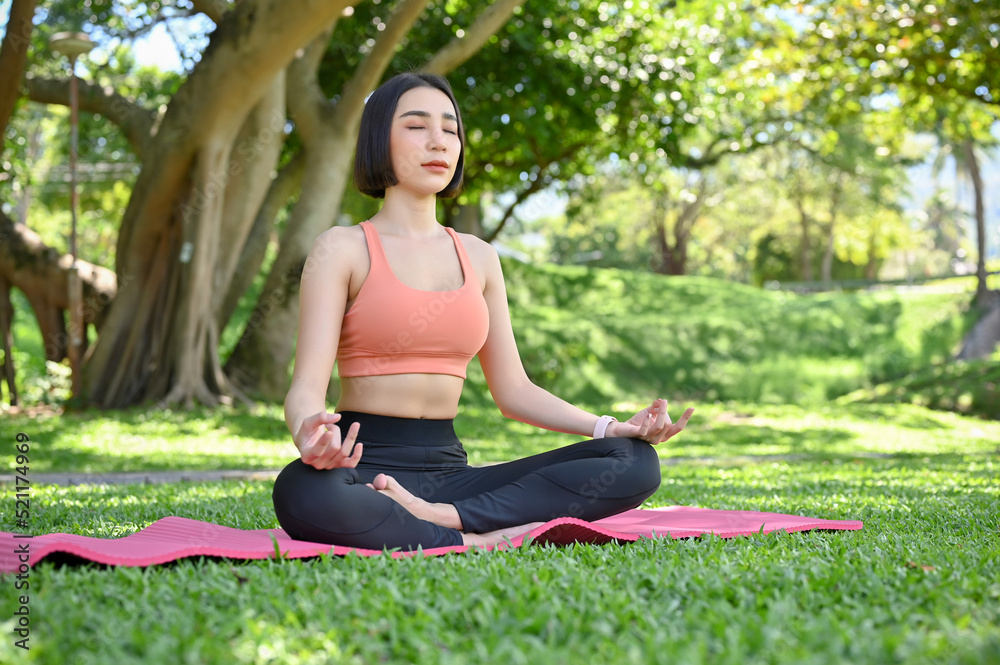 Beautiful and calm Asian female practicing yoga, meditating in the garden. Lotus yoga pose.