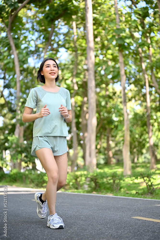 Portrait, Attractive and healthy Asian woman running or jogging on the road in the park.