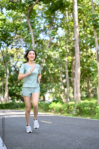 Attractive Asian woman athlete in sportswear running or jogging in the park garden. © bongkarn