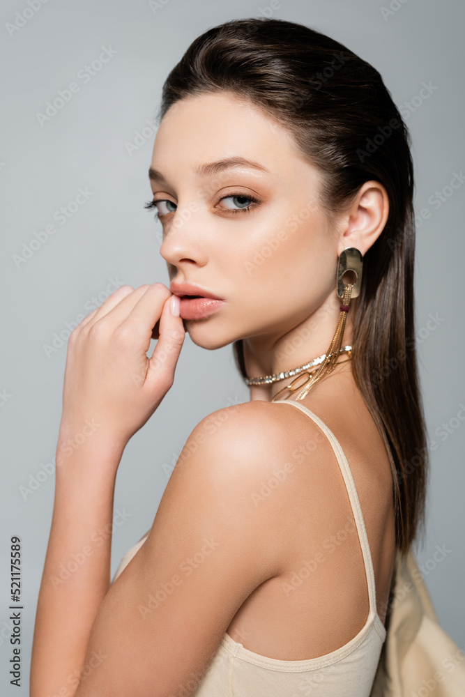 pretty young woman with makeup looking at camera isolated on grey