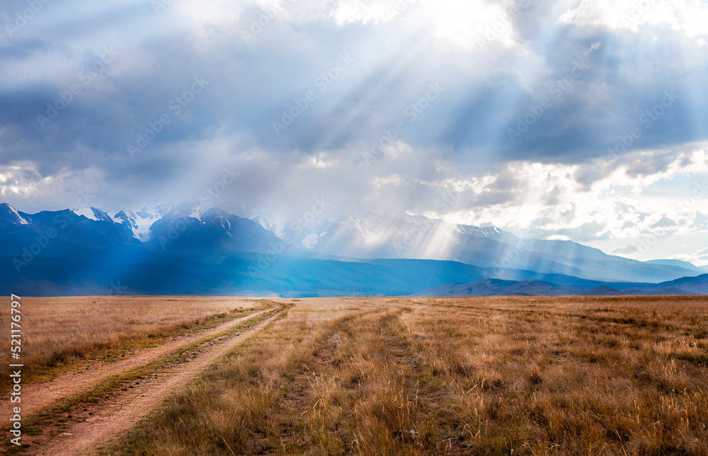 country road in the sun against the backdrop of a mountain landscape