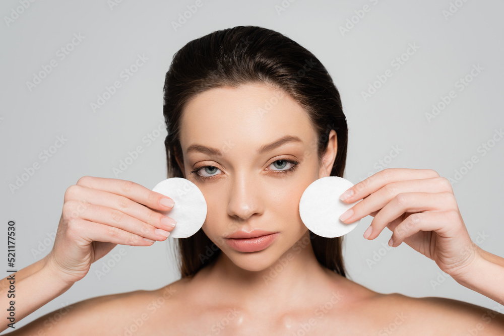 young woman removing makeup with cotton pads isolated on grey young woman removing makeup with cotton pads isolated on grey