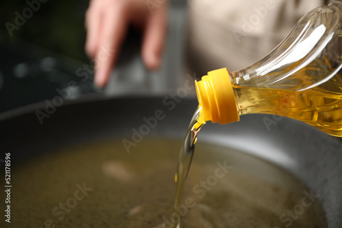 Woman pouring cooking oil from bottle into frying pan, closeup